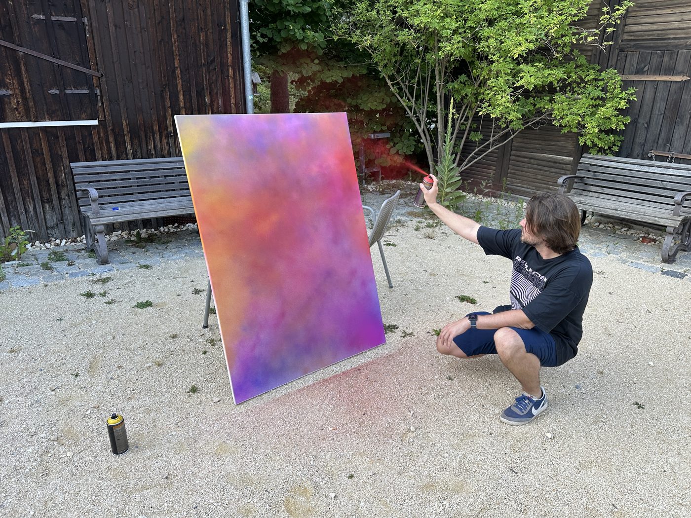 Moritz spray painting a canvas in the atelier courtyard